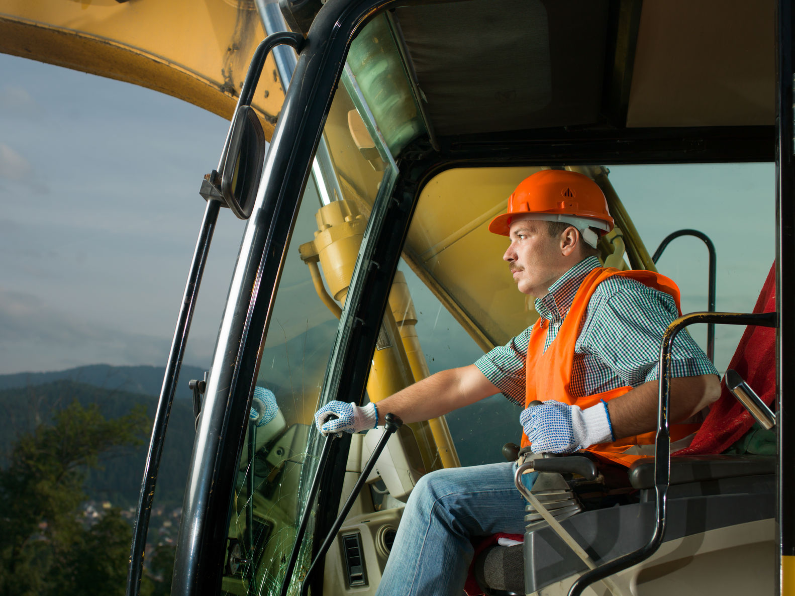 male operator driving excavator on construction building site